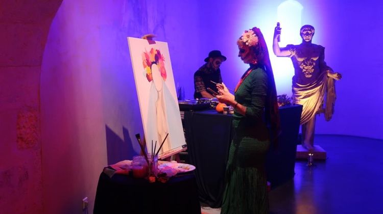 Lors de l'édition Frissons d'automne 2022, une artiste en train de peindre aux côtés d'un DJ déguisés dans une ambiance bleutée